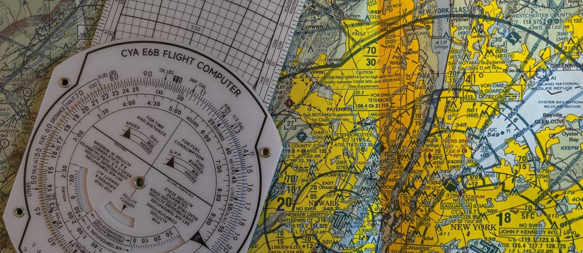 An E6B flight computer lying on a sectional chart of the New York Class B airspace around Newark, Teterboro and LaGuardia.