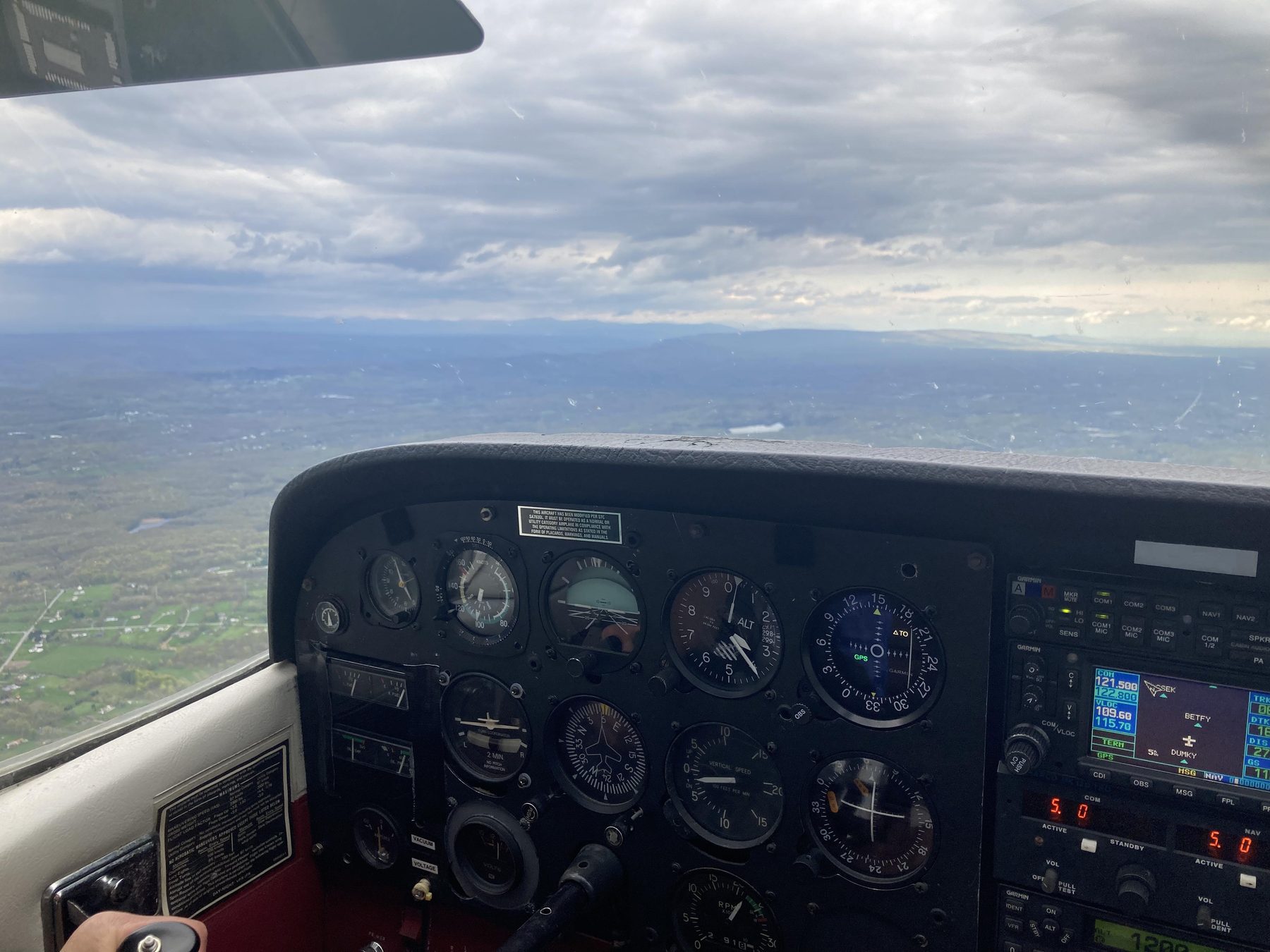 Instrument panel of a Cessna in flight, terrain visible through the windscreen.