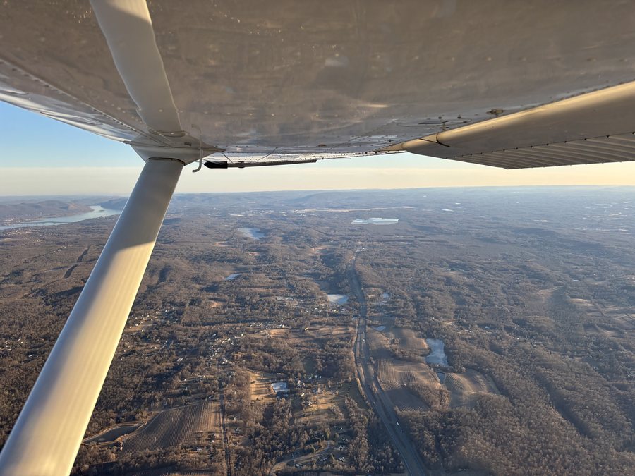 The view over the wing of a training aircraft in flight.